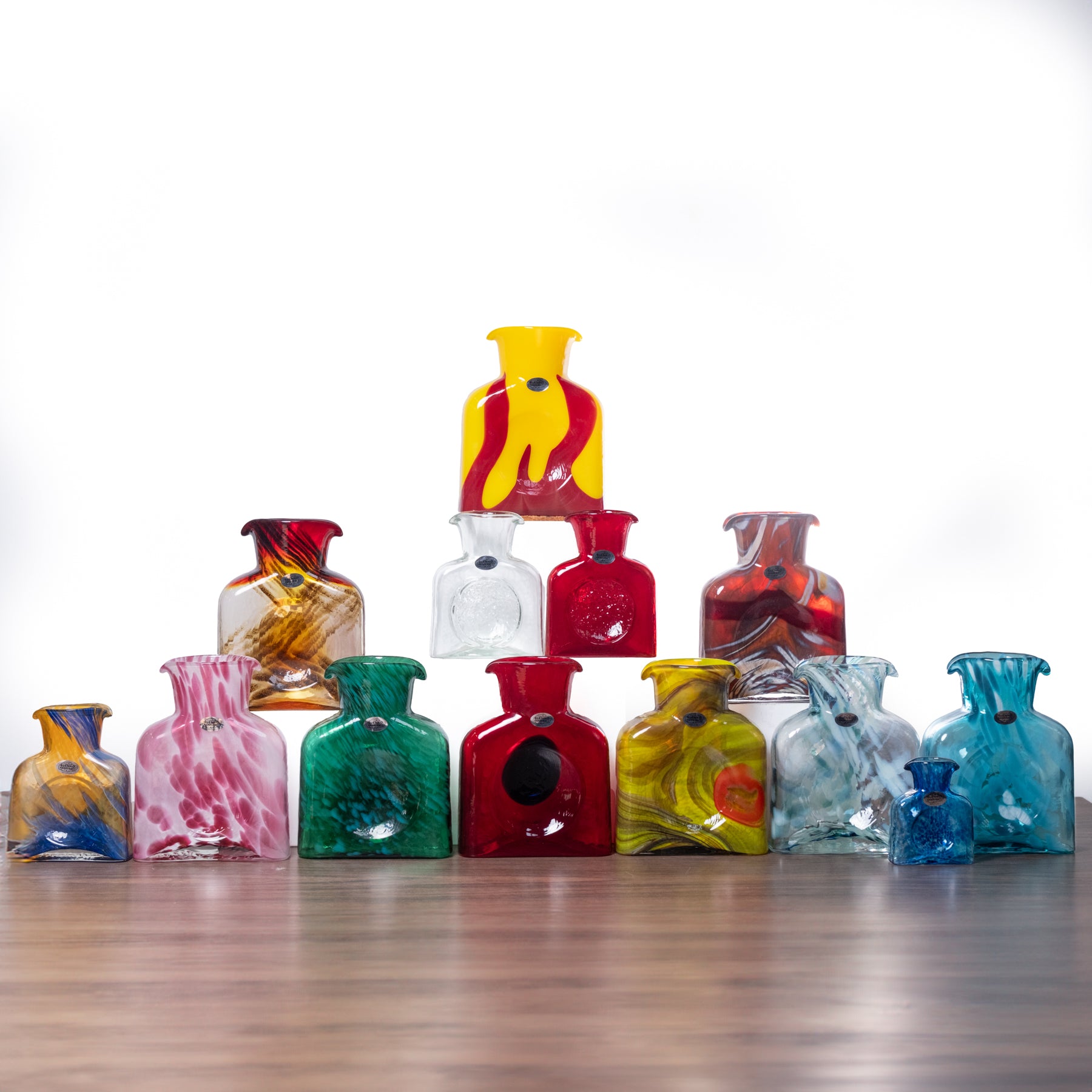 Colorful glass bottles arranged on a wooden surface with a white background