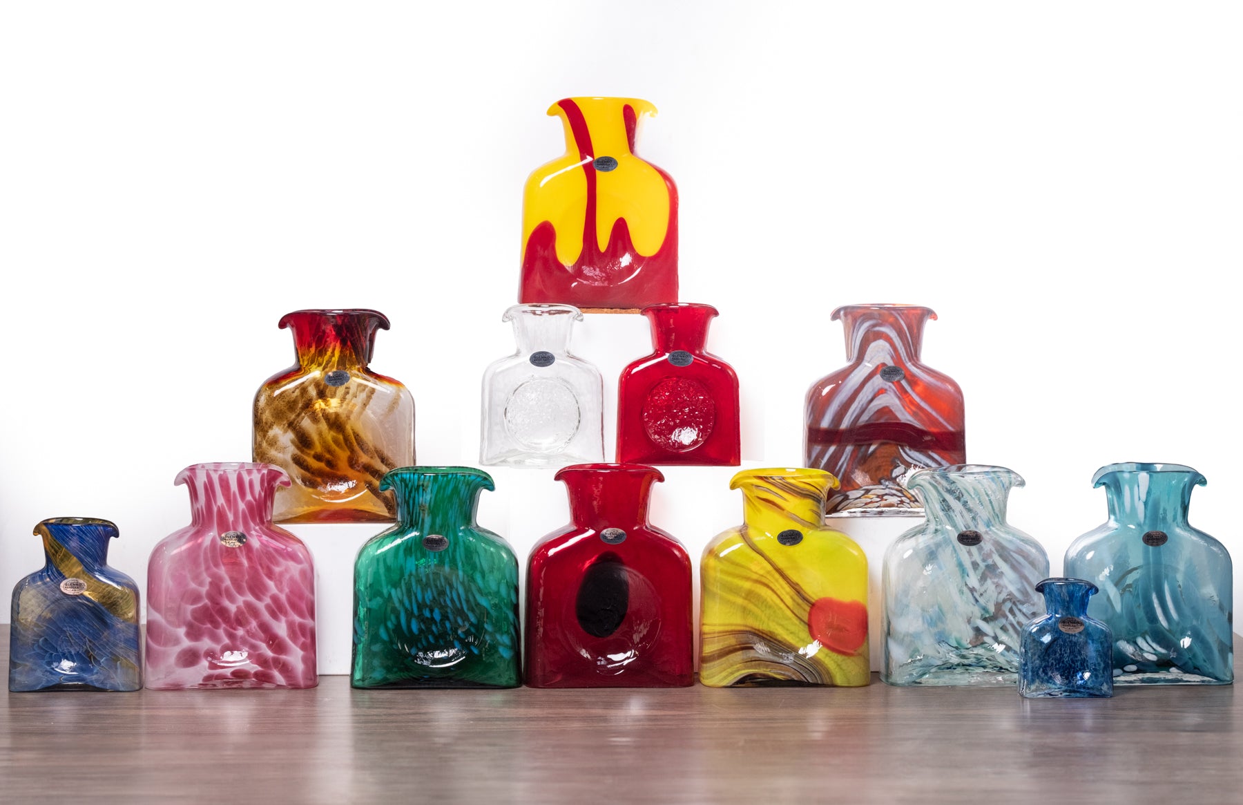 Collection of colorful glass bottles on a wooden surface with a white background
