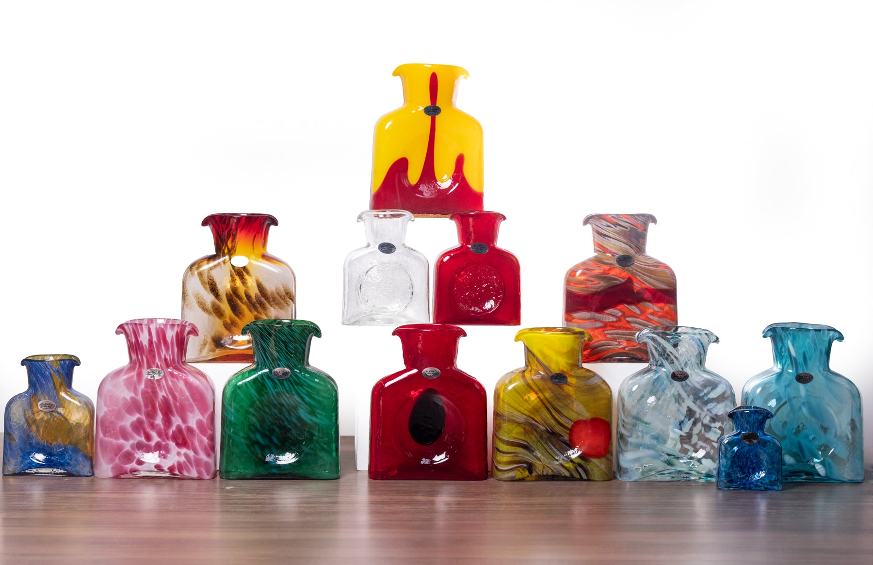 Collection of colorful glass vases on a wooden surface with a white background