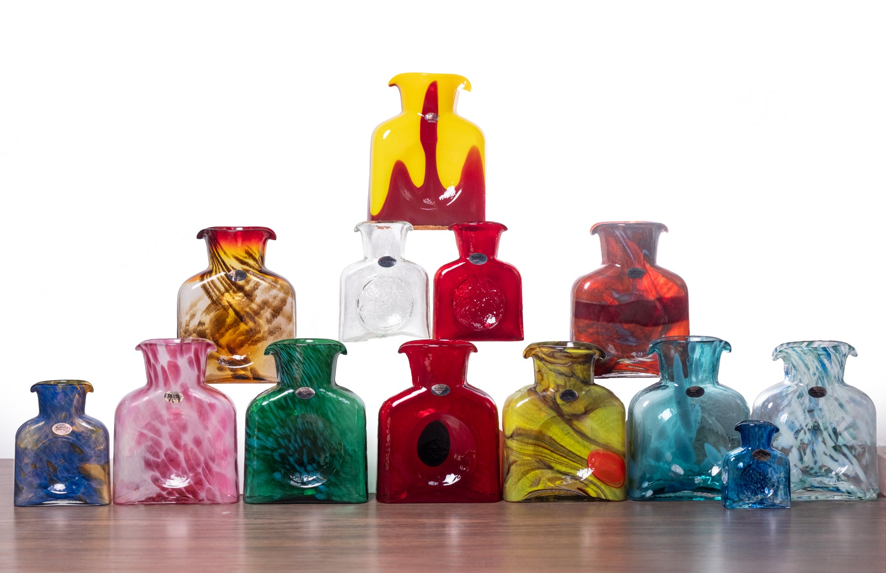 Collection of colorful glass vases on a wooden surface with a white background