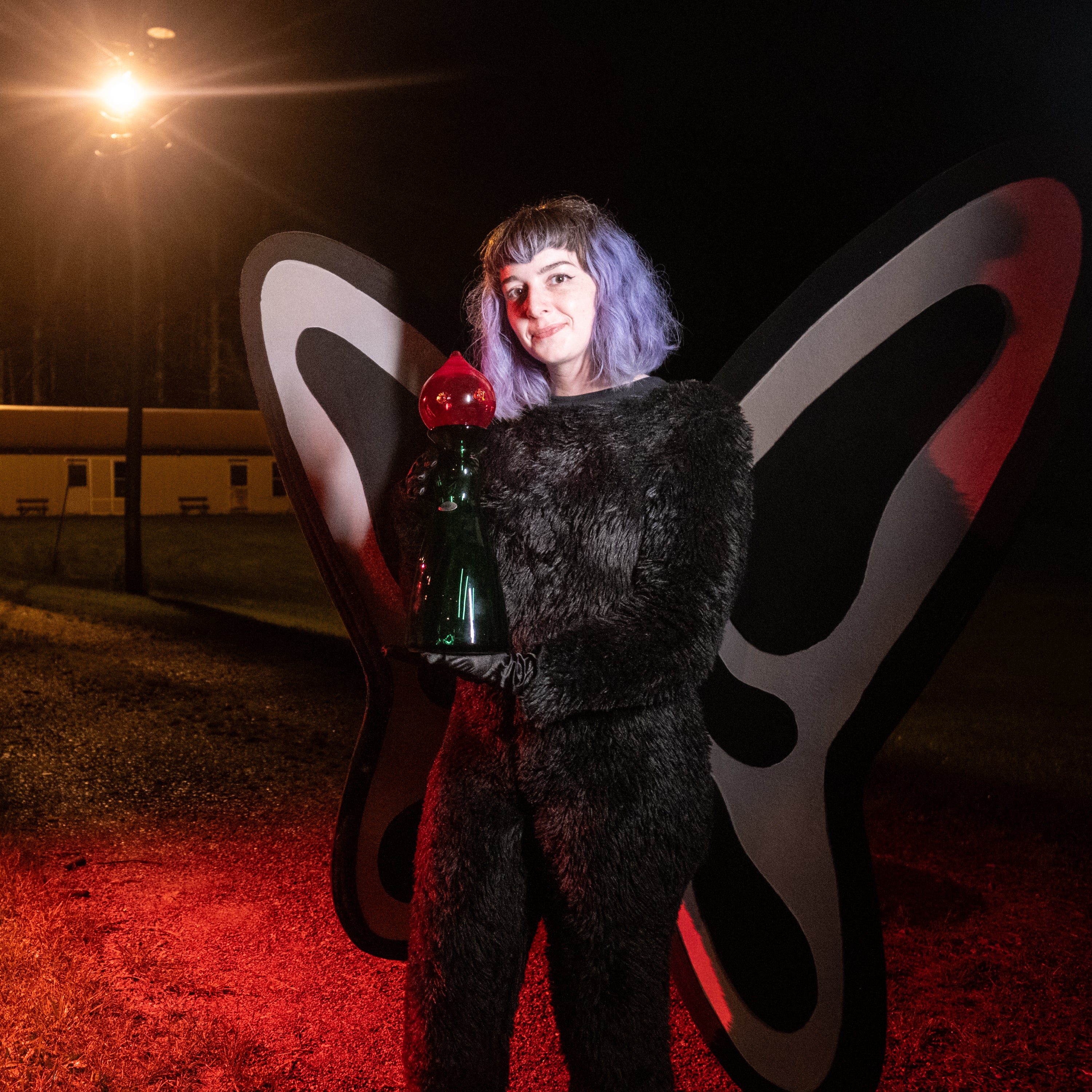 Liz Pavlovic dressed as Mothman holding flat woods monster decanter.