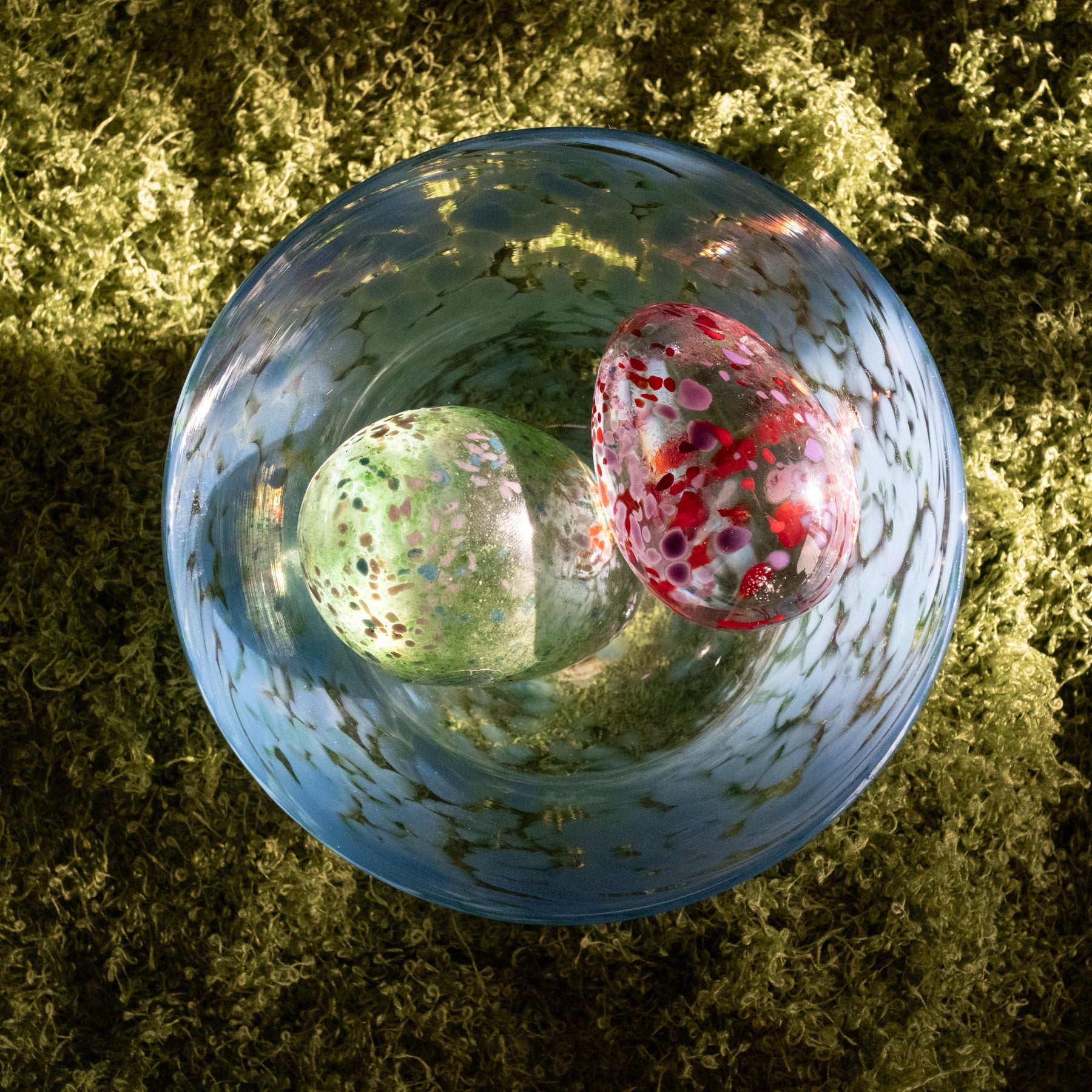 Two glass marbles inside a transparent glass sphere on a green grass background