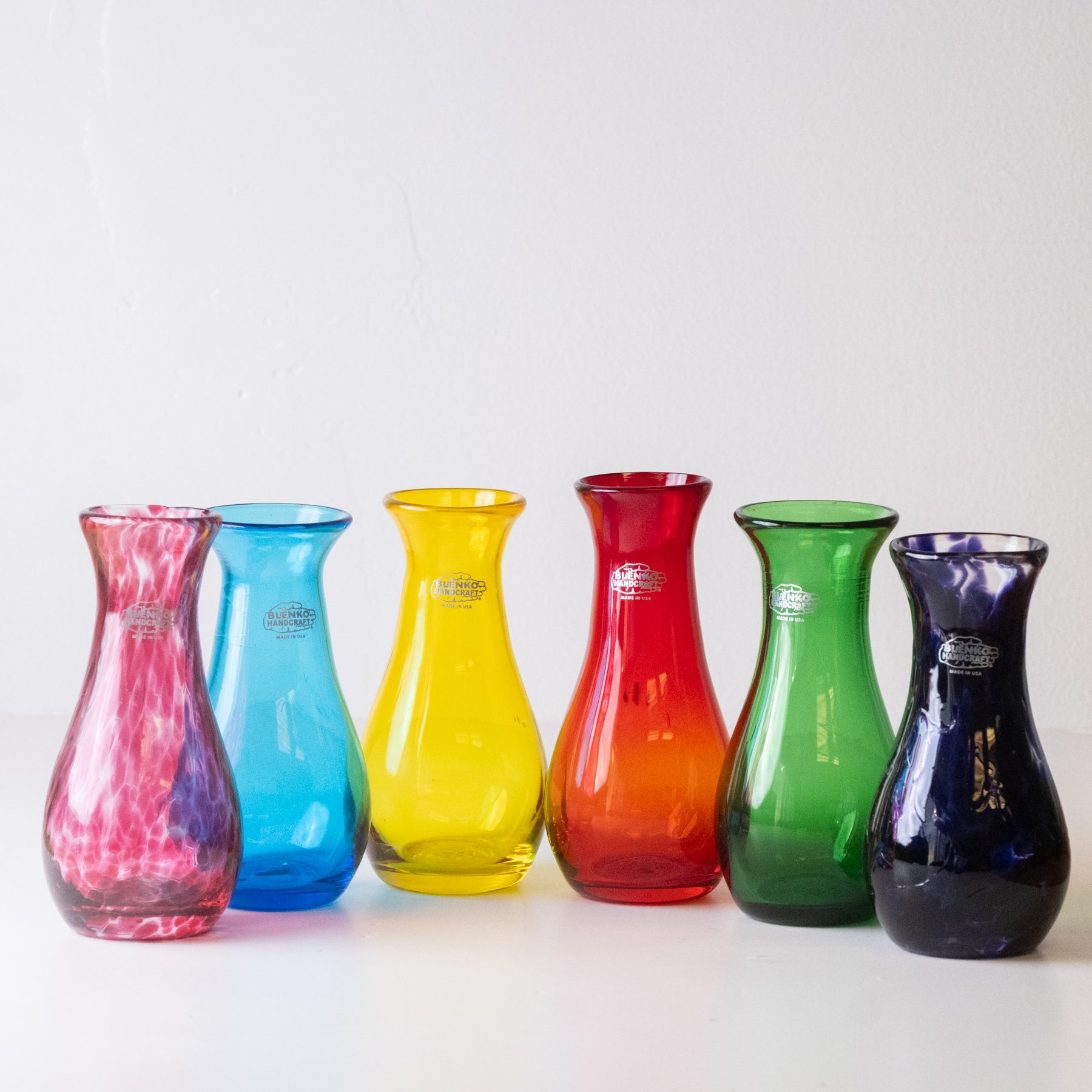Set of six colorful glass vases on a white background