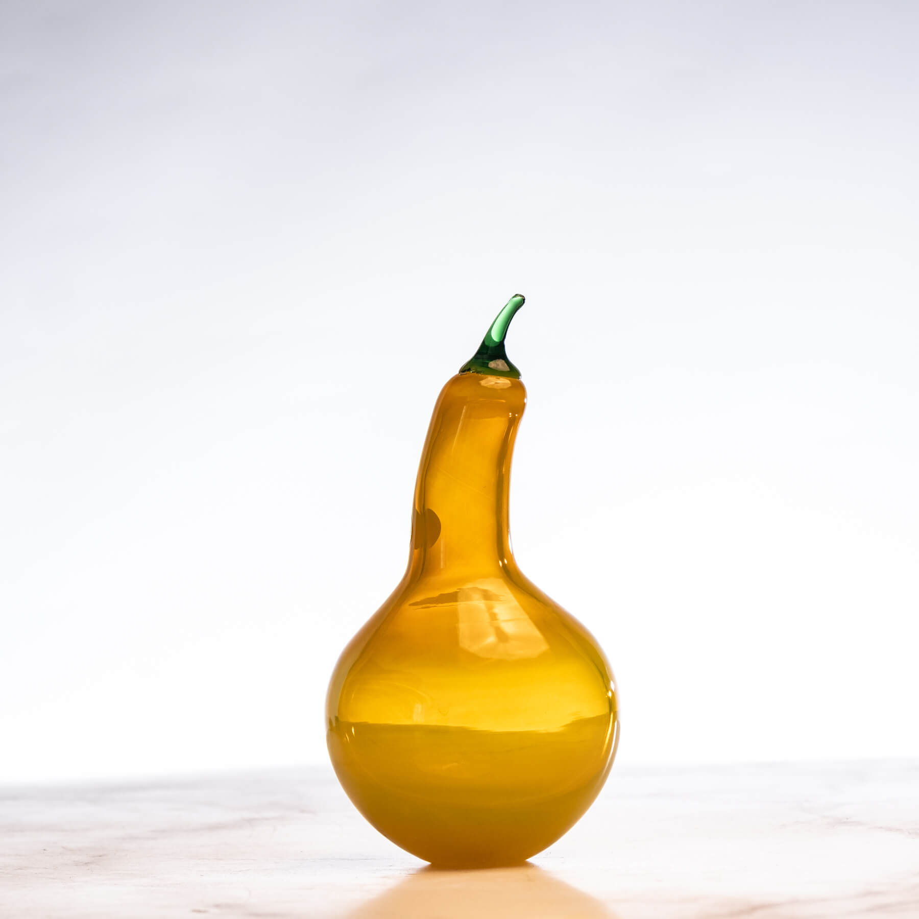 Yellow glass gourd with a green stem on a white background