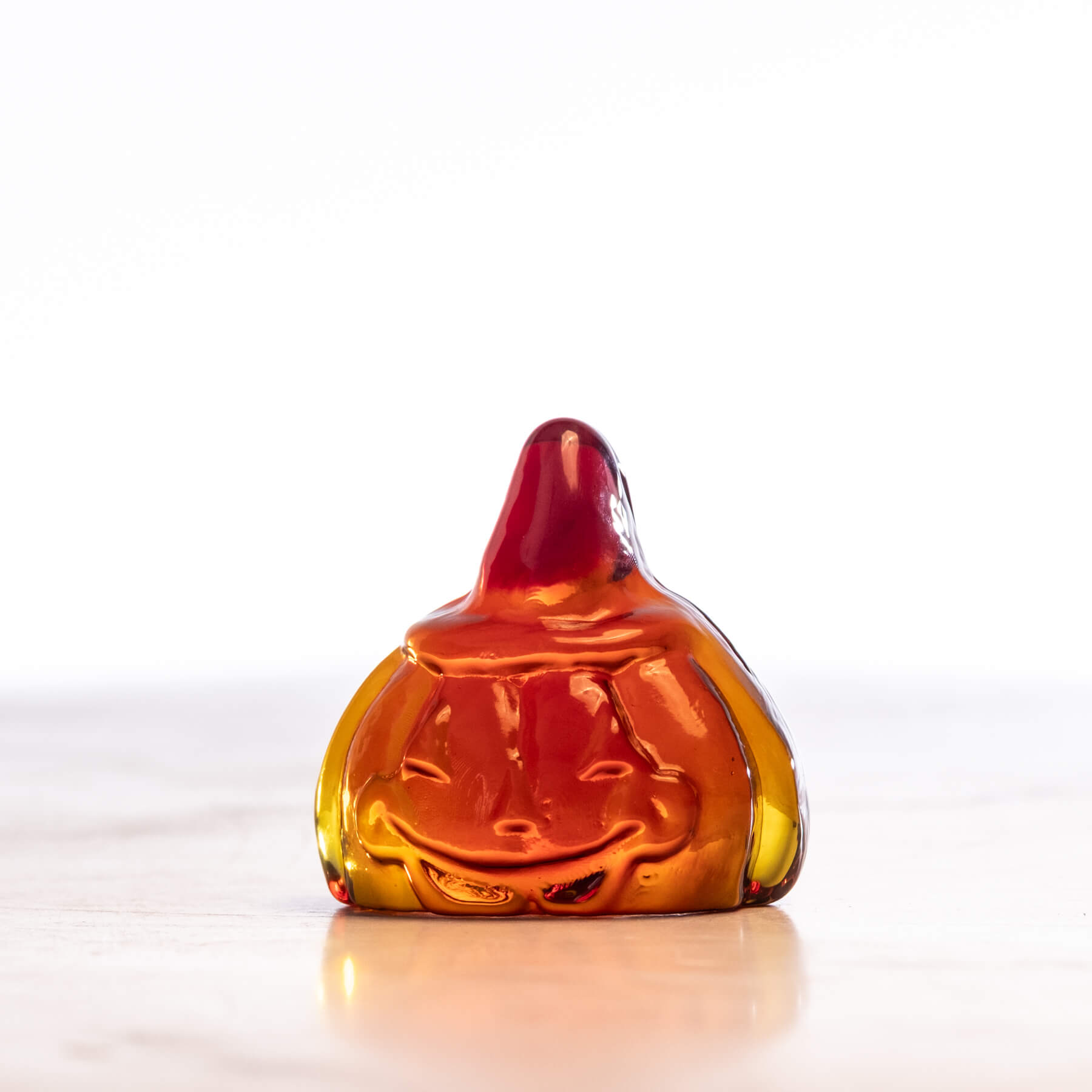 Glass pumpkin figurine with a smiling face on a white background