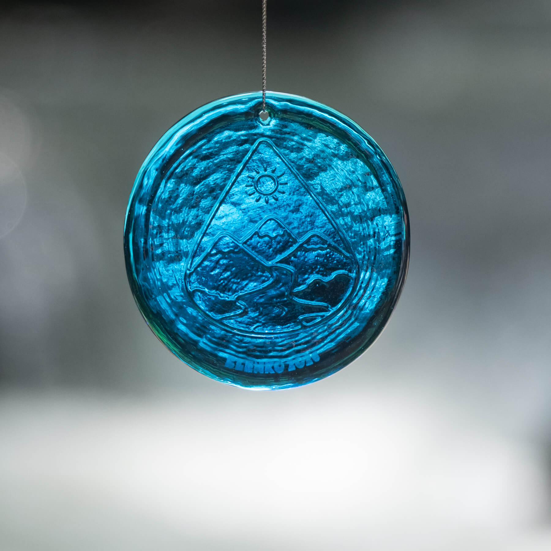 Blue glass ornament with engraved design on a blurred background