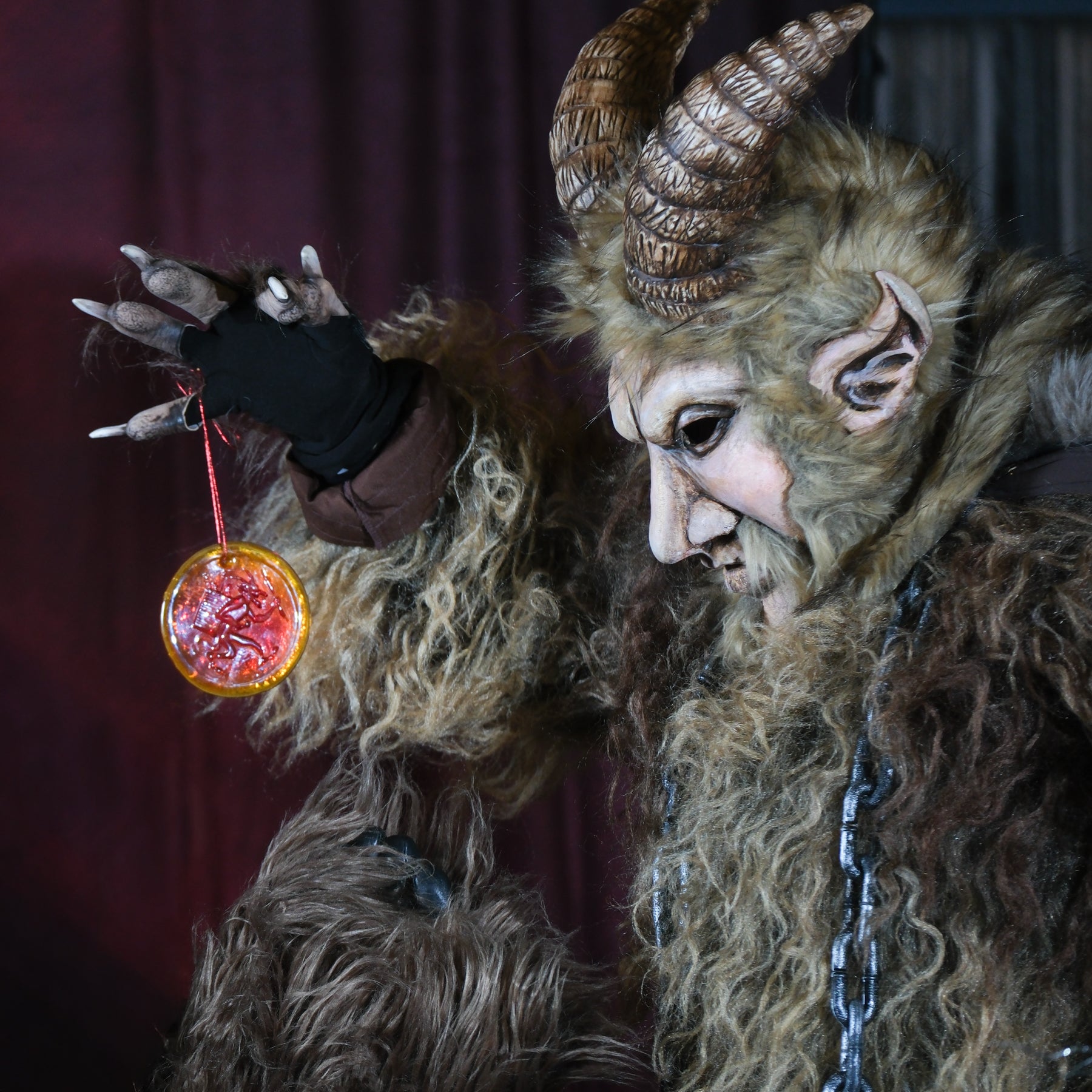 Person in a detailed fantasy costume with horns and fur, holding a glowing orb.